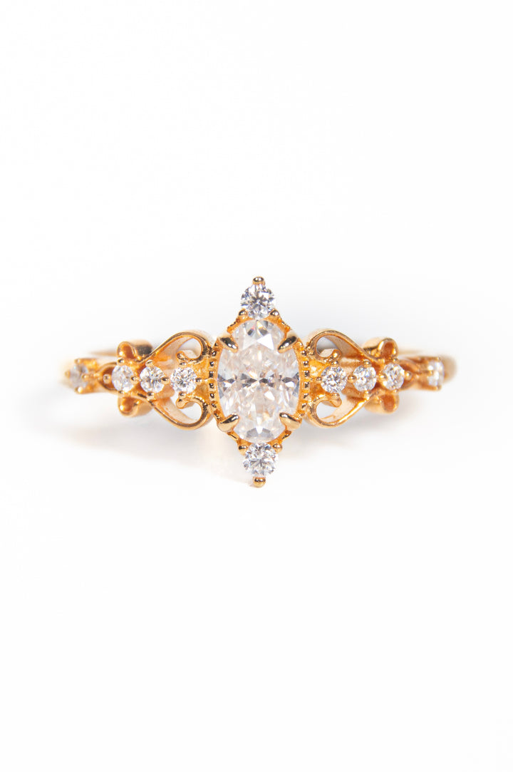 anello in oro, una corona impreziosita con un bellissimo zircone taglio marquise, intagli floreali sulle spallette con pavé di moissanite