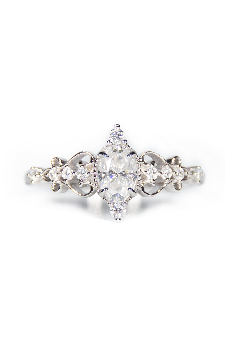 anello in argento placcato oro bianco, una corona impreziosita con un bellissimo zircone taglio marquise, intagli floreali sulle spallette con pavé di moissanite